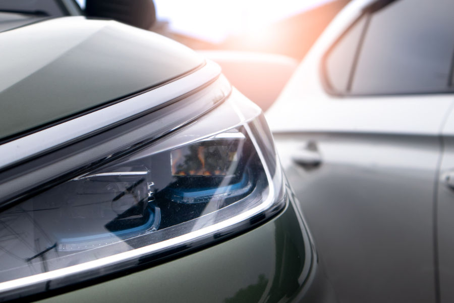 Close up view of modern car headlights with sunbeams in background